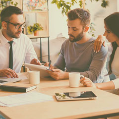 Three employees discussing work over coffee