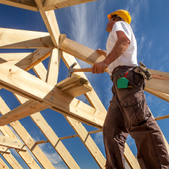 A construction worker building the wooden framework of a house.