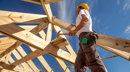 A construction worker building the wooden framework of a house.