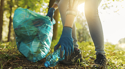 Person picking up trash outdoors