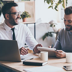 Two employees laughing together in a meeting with coffee