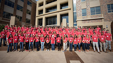 Several dozen D.R.Horton interns standing together in red shirts for a group photo on front of D.R.Horton office.