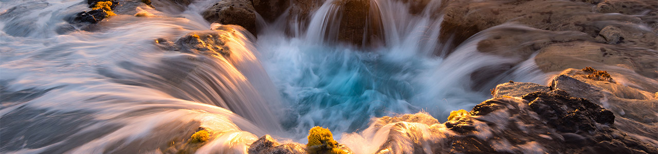 Water flows into a hole on the rocky Hawaiian shoreline.