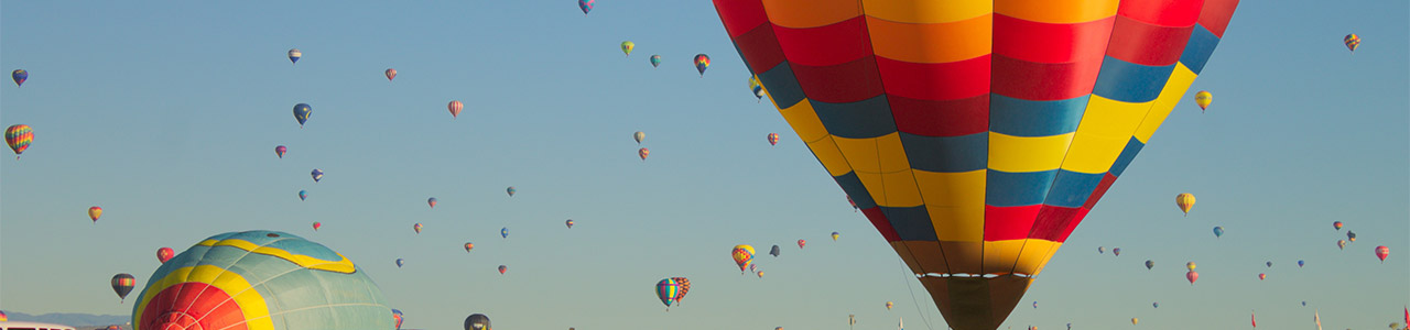 Dozens of hot air ballons rising to the sky from the desert floor.