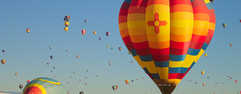 Dozens of hot air balloons rising to the sky from the desert floor.