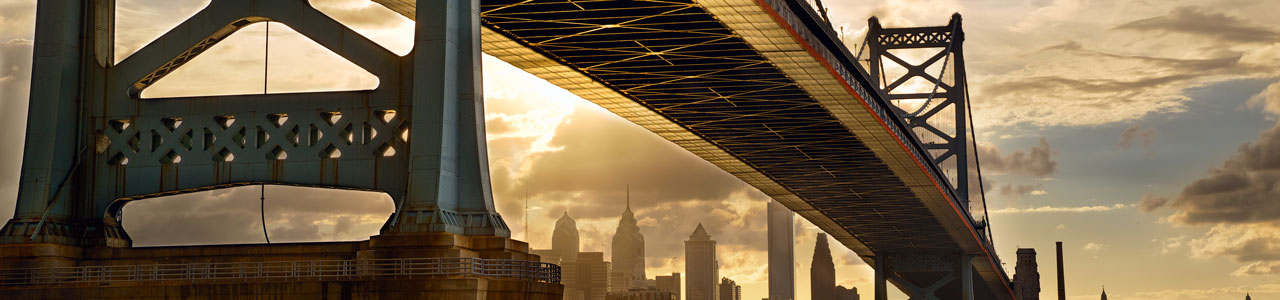 A bridge stretches over a river with downtown Philadelphia in the background.