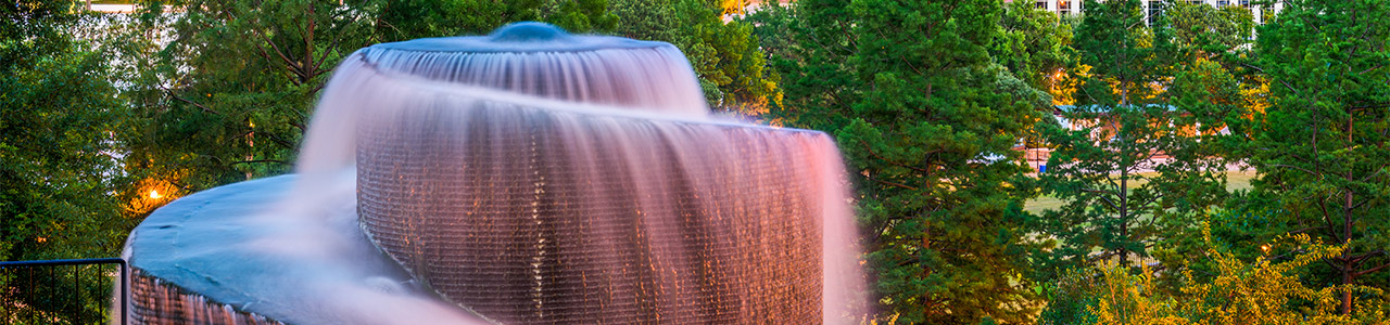 A large fountain with trees behind it.