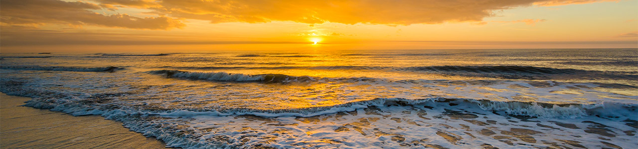 A beachside view of the sunset over the ocean.