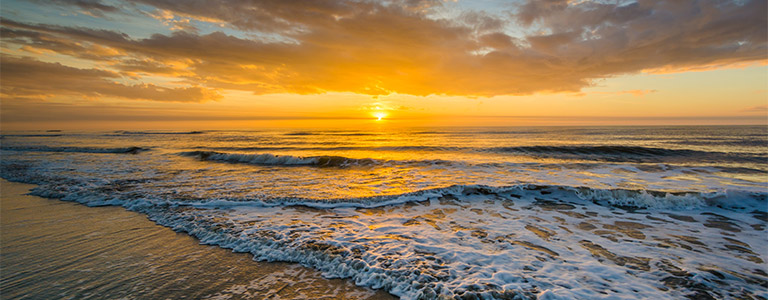 A beachside view of the sunset over the ocean.